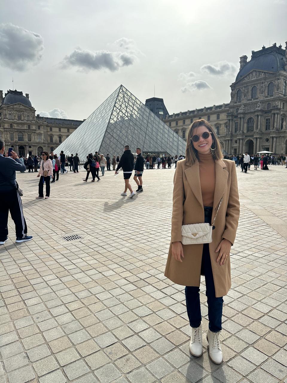 Cliente da Harpya em Paris, em frente à Pirâmide do Louvre